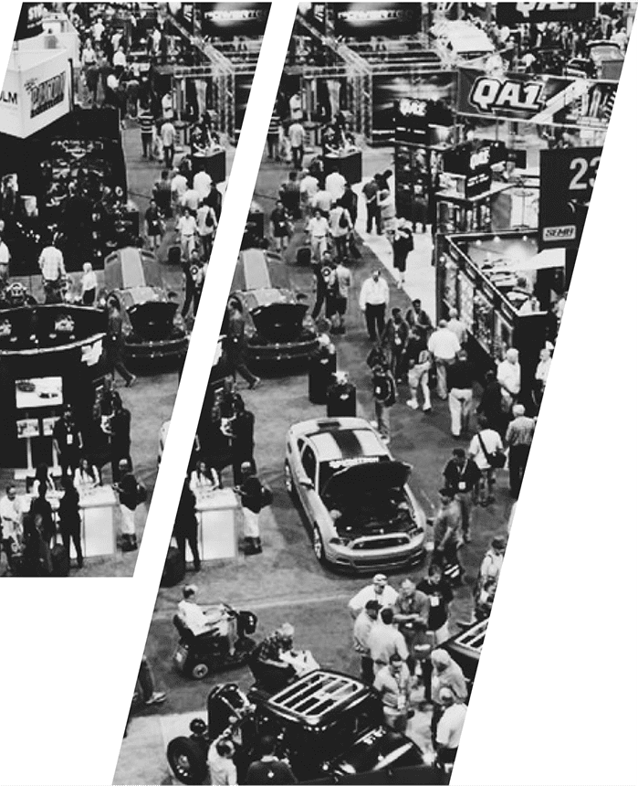A black and white photo of people in an area with cars.