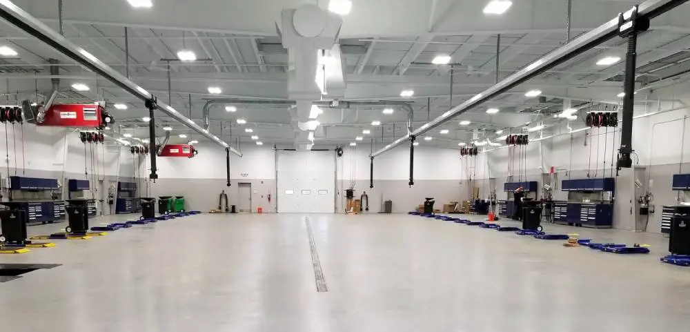 A large warehouse with many lights and a white floor.